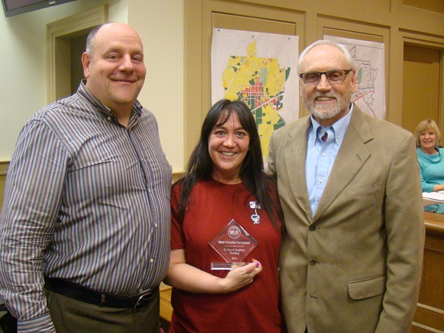 Michelle Cary (center) accepts the 2014 MVP award from Mayor Jim Baskett (right) and Paul Mitchell. 