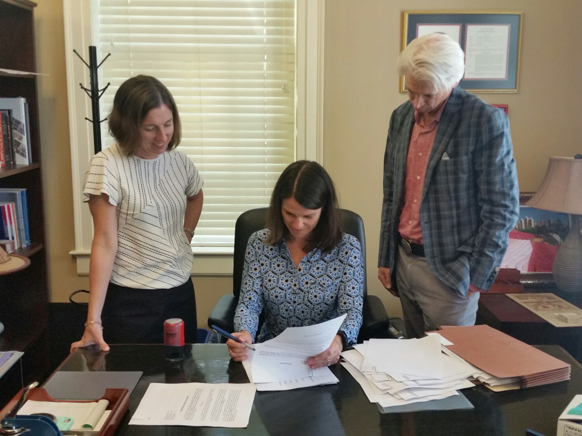 Chair of the City of Decatur Public Facilities Authority Board Meredith Strunk signs the closing documents purchasing the UMCH property. Assistant City Manager Andrea Arnold who serves as Secretary/Treasurer of the PFA and Hutch Moore, closing attorney join her.
